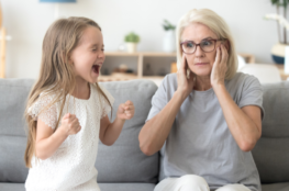 child screaming while mom holds her ears and ignore