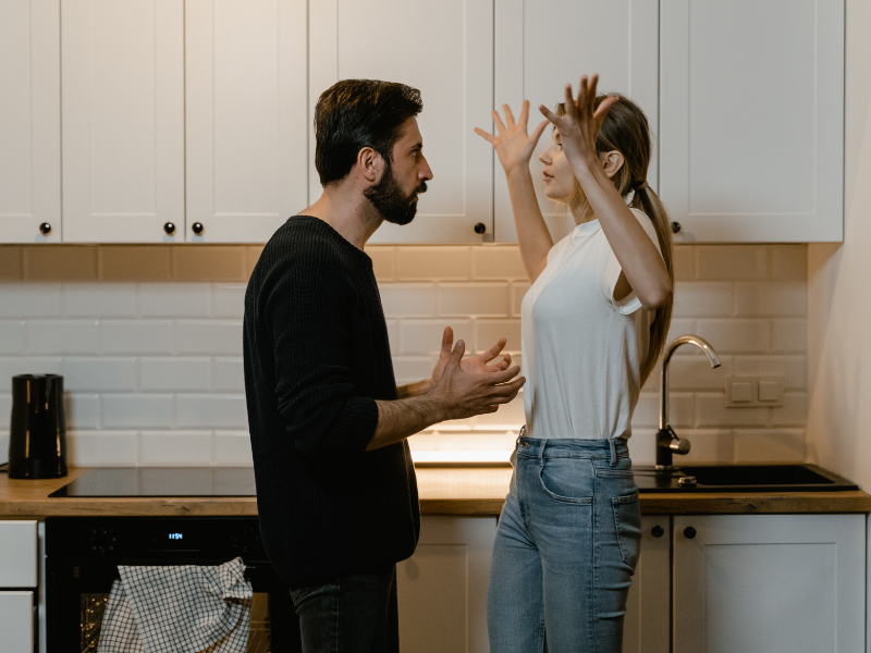 Fighting dirty - a man and woman (couple) standing face to face arguing with their hands in the air