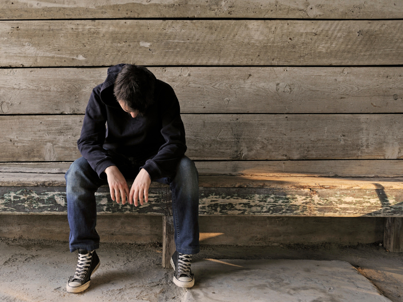 self abandonment - man sitting alone with head hanging down