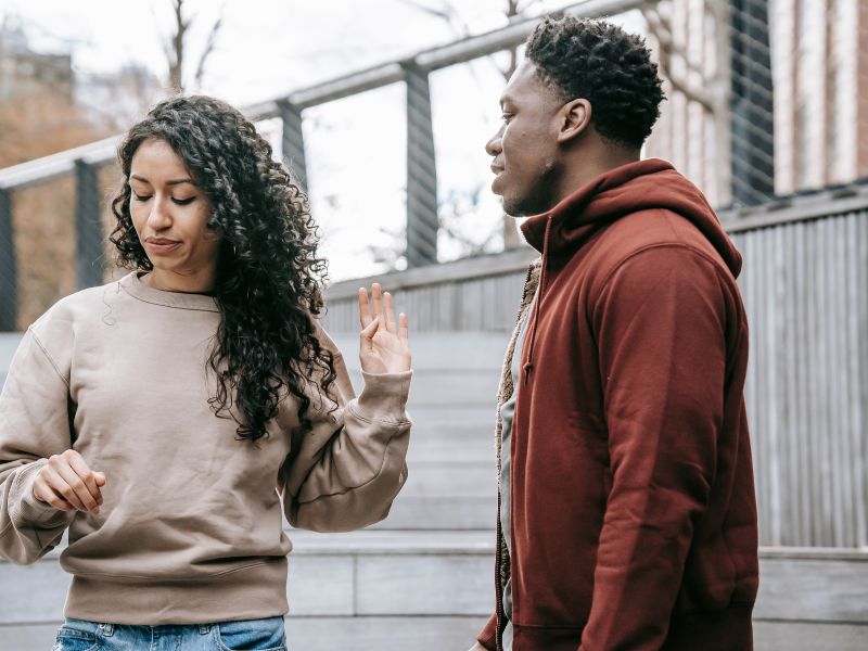 woman turning away from man with hand up